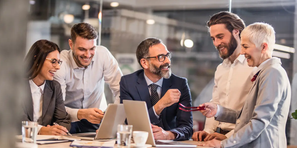 A diverse group of professionals engaged in a lively discussion around a conference table in a modern office setting.